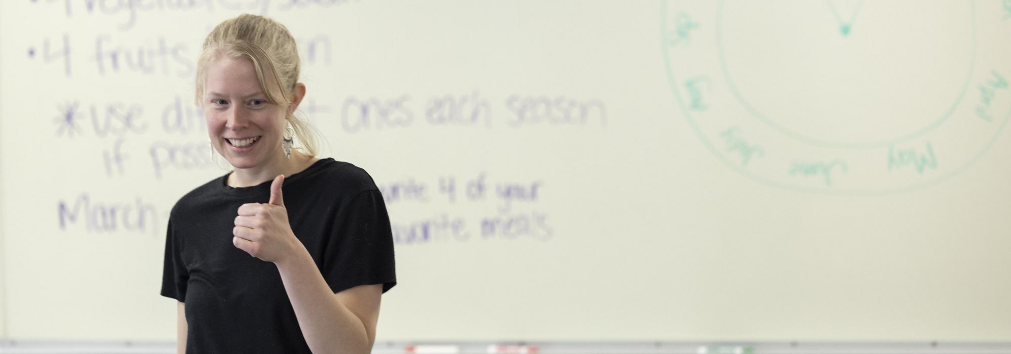 Teacher leans over student in classroom to answer question.