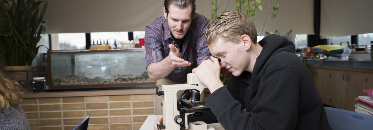Teacher working with student at microscope